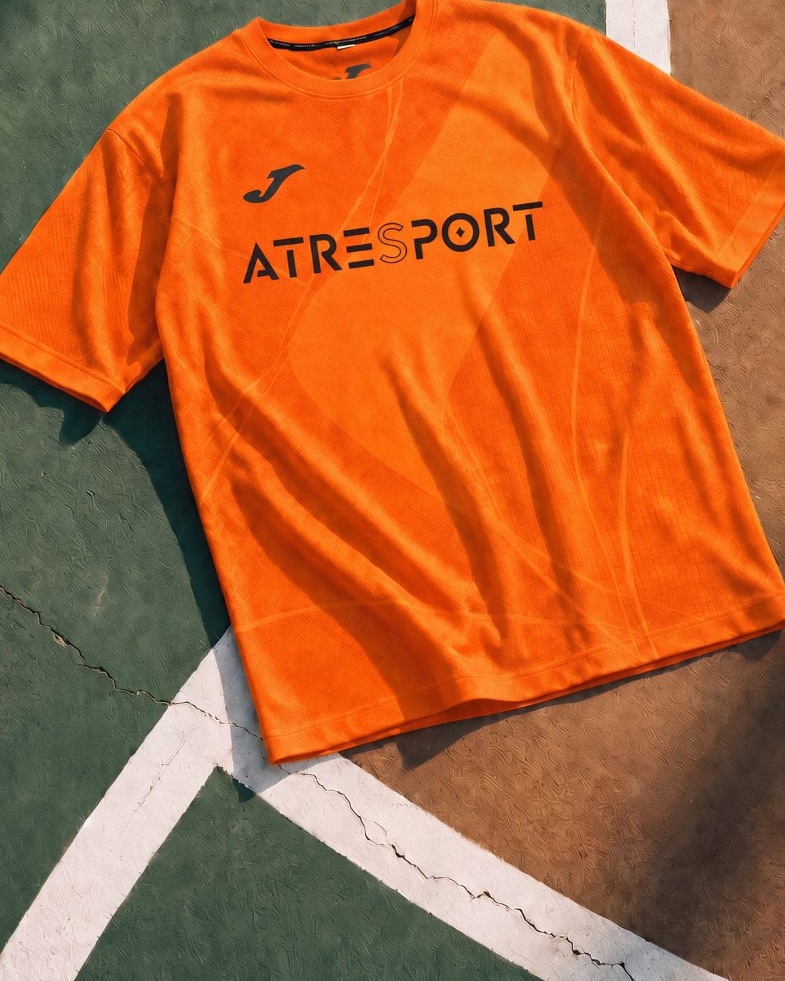 Camiseta de la equipación de ATRESPORT extendida sobre la pista, junto a la línea de fondo.