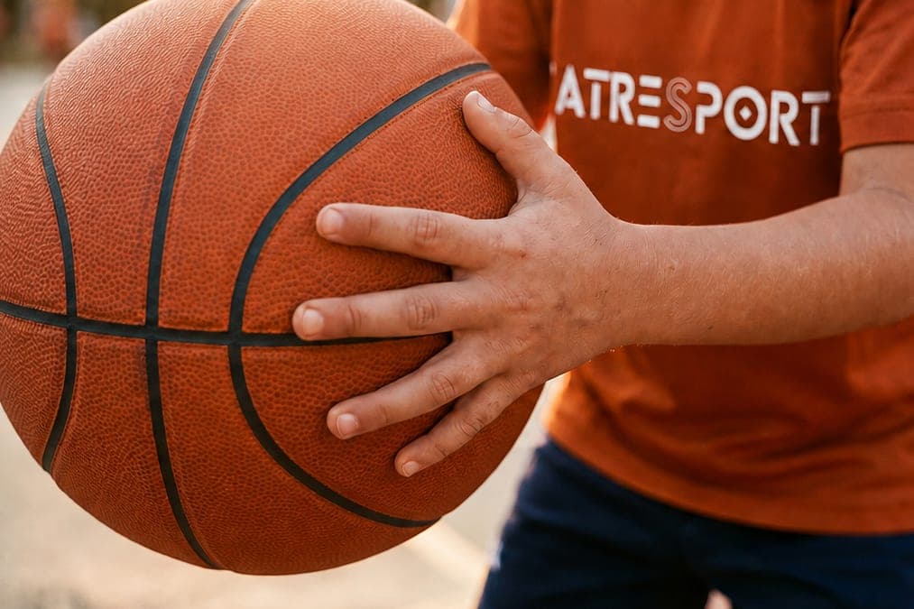 Detalle de las manos de un niño sujetando un balón de baloncesto.