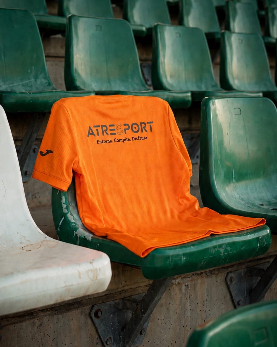 Camiseta de la equipación de ATRESPORT doblada sobre los asientos de una grada.